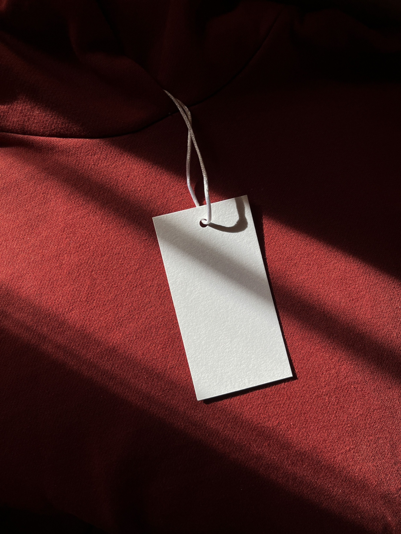 Close-up of a blank white clothing label on a burgundy fabric